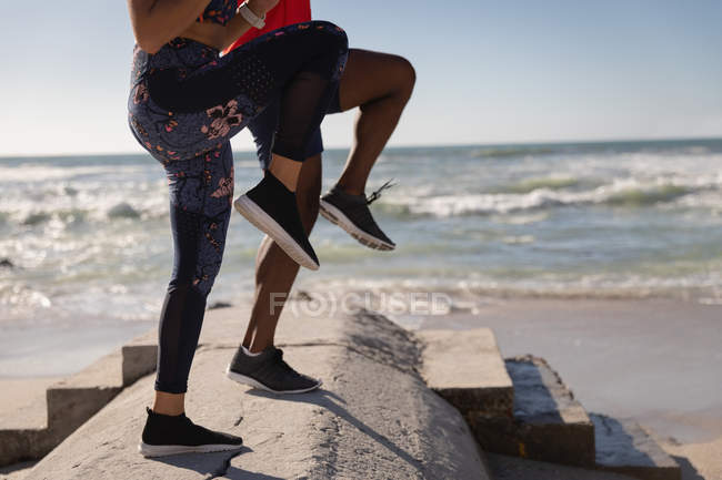 Baixa seção de casal fazendo jogging local na praia — Fotografia de Stock