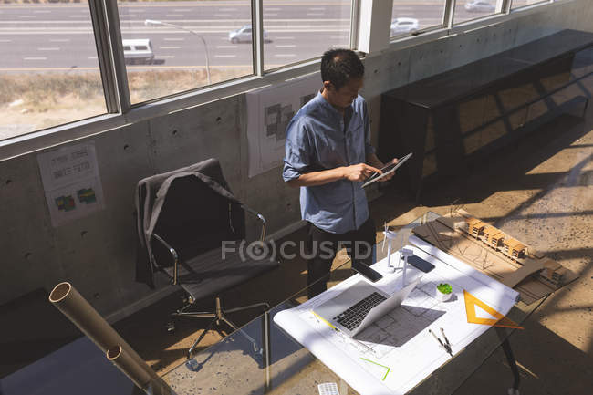 Vista ad alto angolo del giovane dirigente asiatico maschio utilizzando tablet digitale nello studio di architettura — Foto stock
