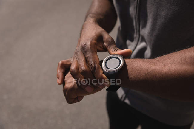 Mid section of man looking at smart watch on street. He sets his watch — Stock Photo