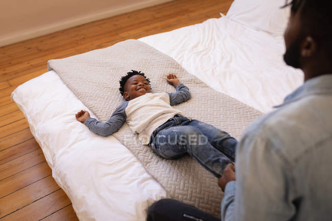 Vista de alto ángulo del padre y el hijo afroamericanos disfrutando en la cama en casa - foto de stock