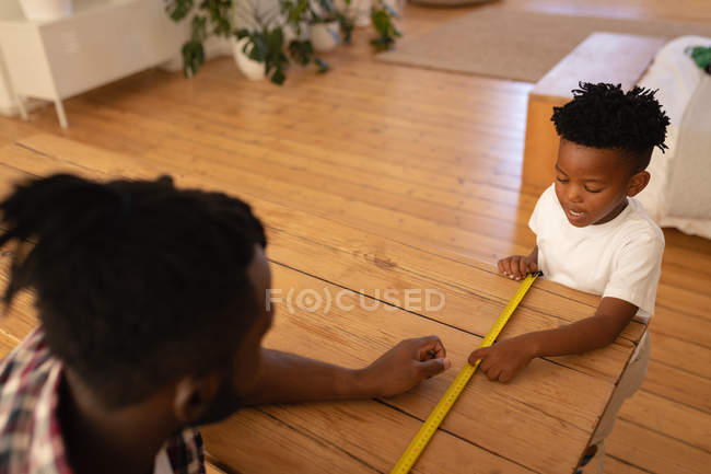 Vista ad alto angolo del tavolo di misurazione padre e figlio afroamericano con nastro di misurazione — Foto stock