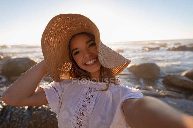Portrait of happy woman standing at beach. She is smiling and looking at camera — Stock Photo