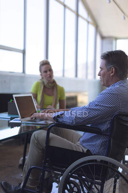 Deficiente caucasiano masculino e branco feminino executivo interagindo uns com os outros no escritório — Fotografia de Stock