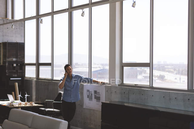 Visão frontal do jovem executivo asiático falando no telefone celular no escritório — Fotografia de Stock
