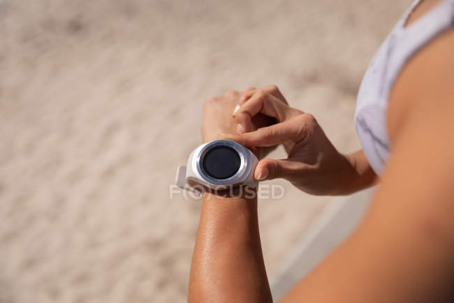 Крупный план женщины, использующей умные часы на пляже — стоковое фото