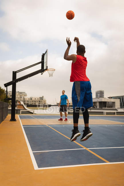 Rückansicht eines afrikanisch-amerikanischen Basketballspielers, der schießt, während ein anderer Spieler seinen Schuss auf dem Spielplatz betrachtet — Stockfoto