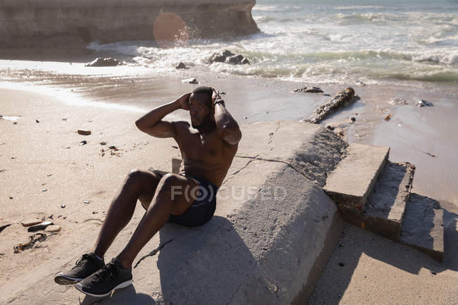 Frontansicht eines afrikanisch-amerikanischen Mannes, der an einem sonnigen Tag am Strand Sport treibt — Stockfoto