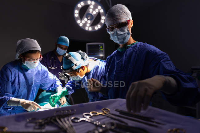 Side view of surgeons concentrated performing operation in operating room at hospital — Stock Photo