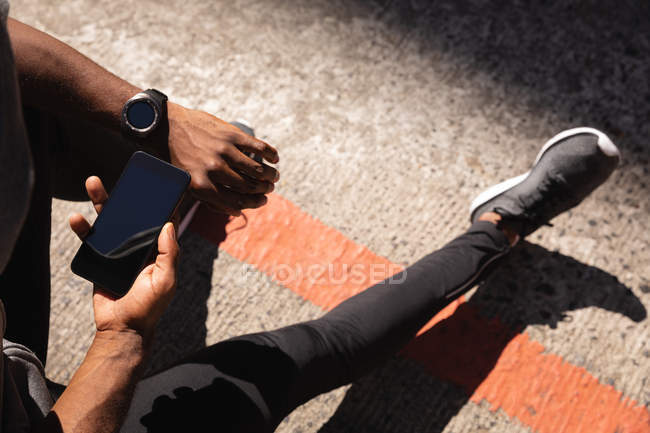 Vue grand angle de l'homme utilisant un téléphone portable tout en se relaxant dans la rue — Photo de stock