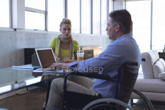 Disabili caucasico maschio e caucasico donna esecutivo interagire con l'altro in ufficio — Foto stock