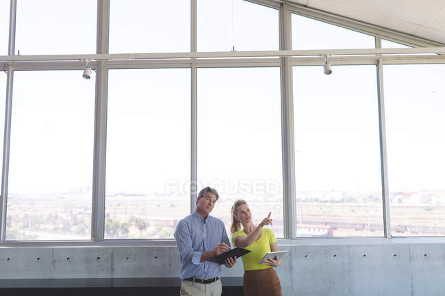 Vista frontal de maduro branco masculino e branco loira arquitetos do sexo feminino interagindo uns com os outros no escritório — Fotografia de Stock