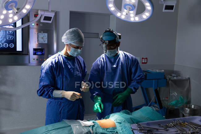 Vista frontal dos cirurgiões que realizam operação em centro cirúrgico no hospital — Fotografia de Stock