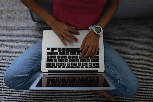 Hochwinkelaufnahme einer Frau mit Laptop, die zu Hause auf dem Boden sitzt — Stockfoto