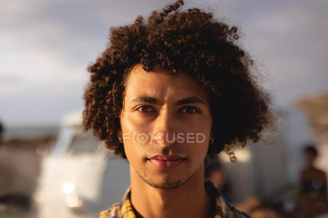 Porträt eines Mannes mit gemischter Rasse, der an einem sonnigen Tag am Strand steht und in die Kamera blickt — Stockfoto