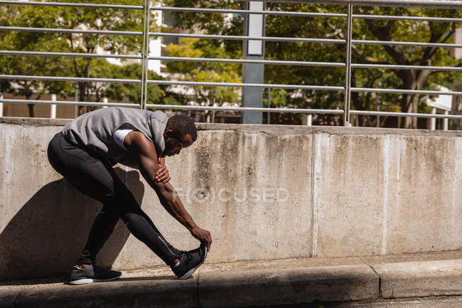 Vista lateral do homem afro-americano fazendo exercício de alongamento na caminhada lateral — Fotografia de Stock