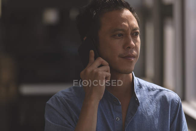 Primer plano del arquitecto asiático hablando por teléfono móvil en una oficina moderna - foto de stock