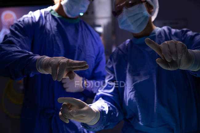 Milieu de la section des chirurgiens parlant entre eux pendant la chirurgie dans la salle d'opération à l'hôpital — Photo de stock