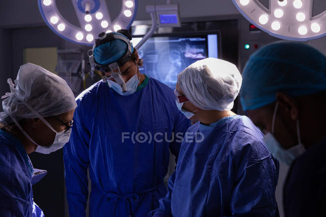 Вид спереду хірургів, що розмовляють один з одним під час операції в операційній кімнаті в лікарні — стокове фото