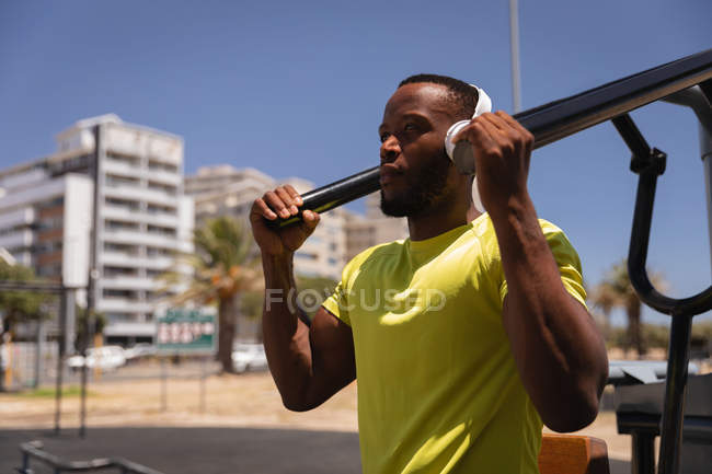 Vue latérale du jeune homme en forme afro-américain faisant de l'exercice dans le parc par une journée ensoleillée — Photo de stock