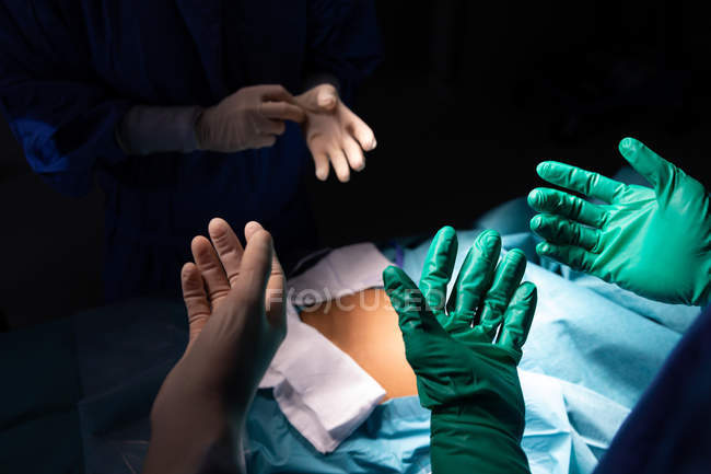 Gros plan des chirurgiens portant des gants chirurgicaux en salle d'opération à l'hôpital — Photo de stock