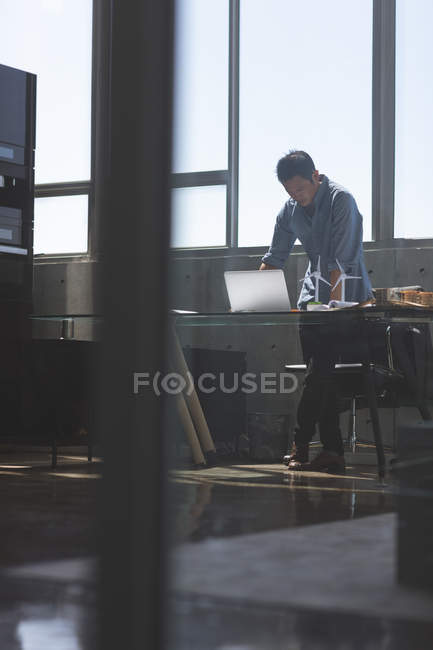 Front view of male asian architect standing and working at desk in a modern office — Stock Photo