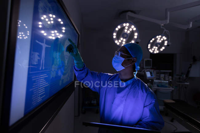 Вид спереди хирурга, смотрящего на синий цифровой экран в операционной в больнице — стоковое фото