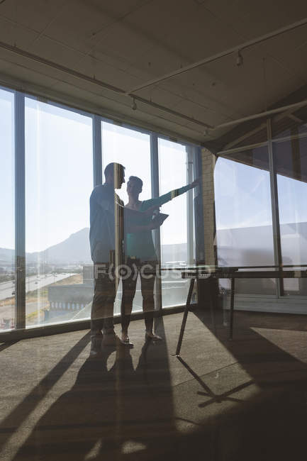Low angle view of Caucasian architects discussing over a digital tablet and looking at the office while interacting together — Stock Photo