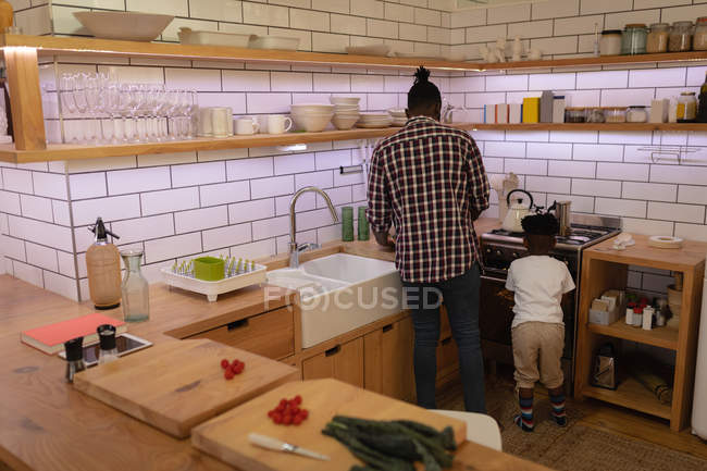 Rear view of African-American father and son cooking together in kitchen at home — Stock Photo