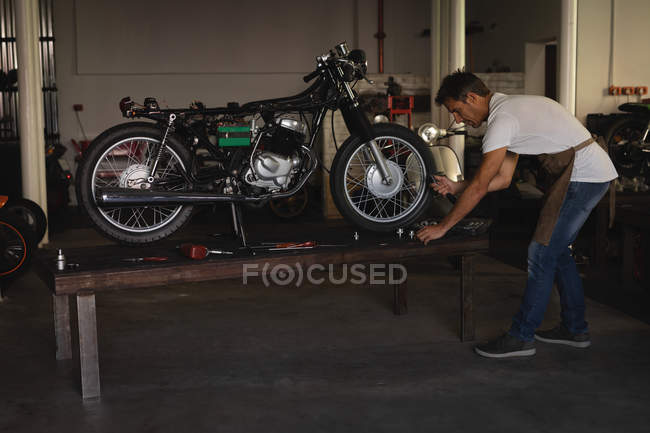 Side view of Caucasian bike Mechanic repairing bike in garage — Stock Photo