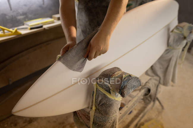 Середина людини прибирає дошку для серфінгу з тканиною в майстерні — стокове фото