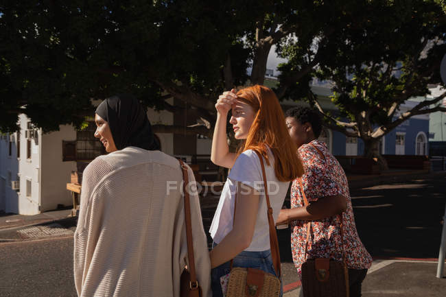Rear view of mixed race female friends looking with shielding eye — Stock Photo