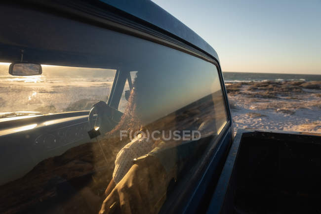 Вид збоку романтичної молодої афроамериканської пари водіння в автомобілі на пляжі в сонячний день — стокове фото
