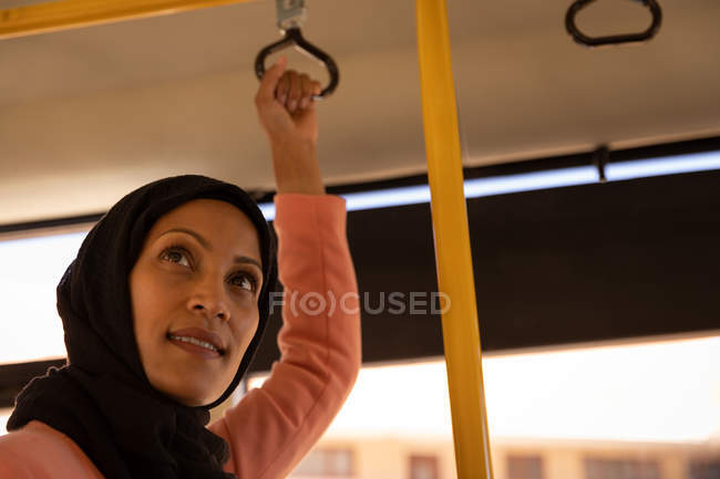 Low angle view of a beautiful mixed-race woman standing in the bus — Stock Photo