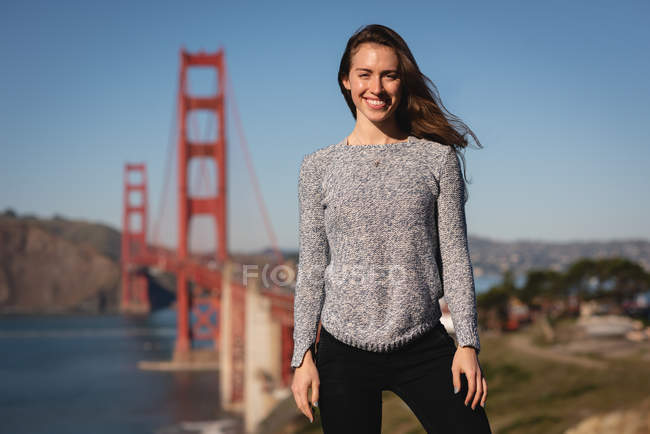 Portrait of beautiful woman smiling and standing near suspension bridge — Stock Photo
