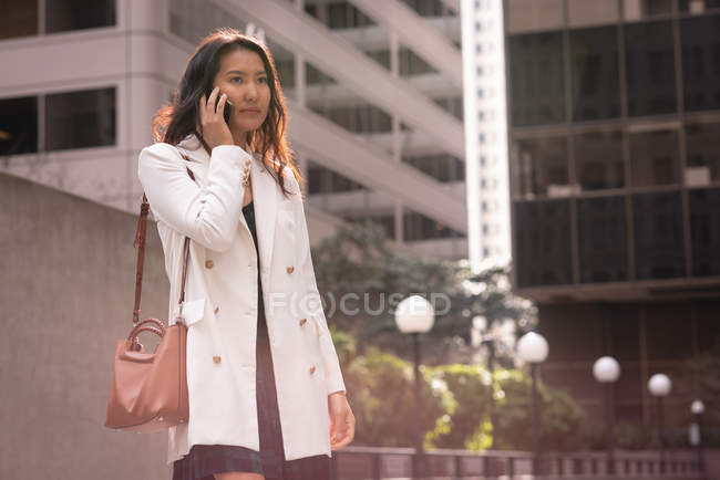 Vista frontal da mulher asiática usando telefone celular enquanto está na rua — Fotografia de Stock