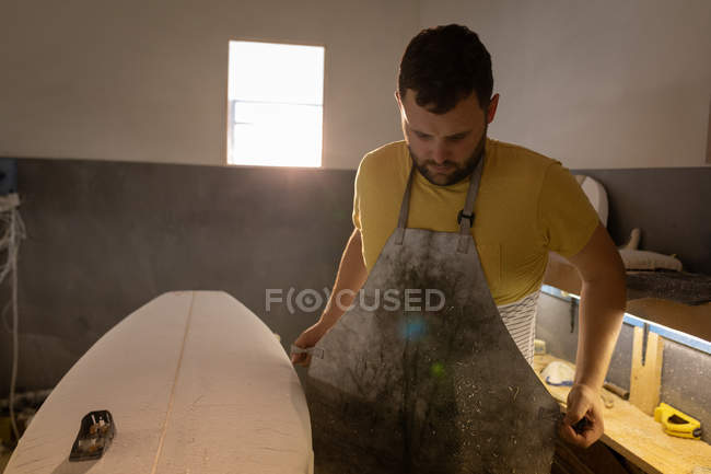 Front view of Caucasian man putting apron on while looking down in a workshop — Stock Photo