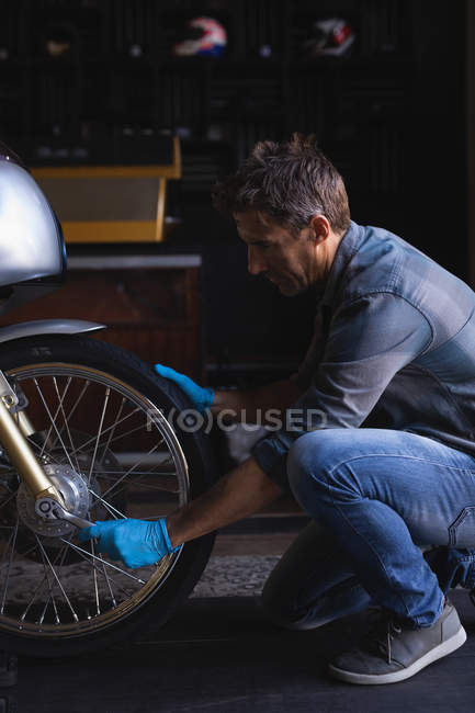 Seitenansicht des kaukasischen Fahrradmechanikers mit Ratschenschlüssel zum Einstellen des Fahrradreifens — Stockfoto