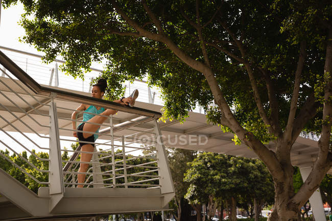 Vue à angle bas de la jeune femme de race mixte faisant de l'exercice sur les escaliers dans la ville — Photo de stock