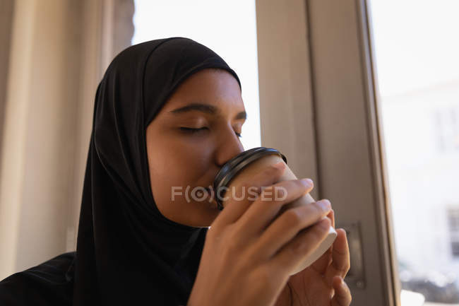 Profil de belle jeune femme à hijab prenant un café dans un café — Photo de stock