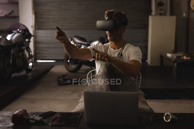 Vue de face du mécanicien masculin caucasien utilisant un casque de réalité virtuelle dans le garage — Photo de stock