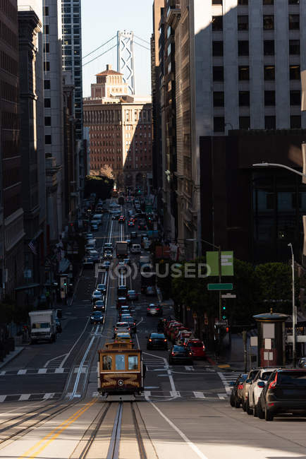 Tranvía y vehículo moviéndose en una calle concurrida de la ciudad en un día soleado - foto de stock