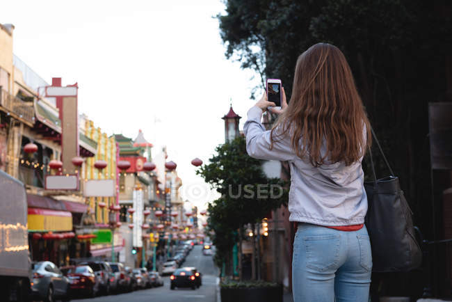 Vista trasera de la mujer que captura la foto de la ciudad - foto de stock