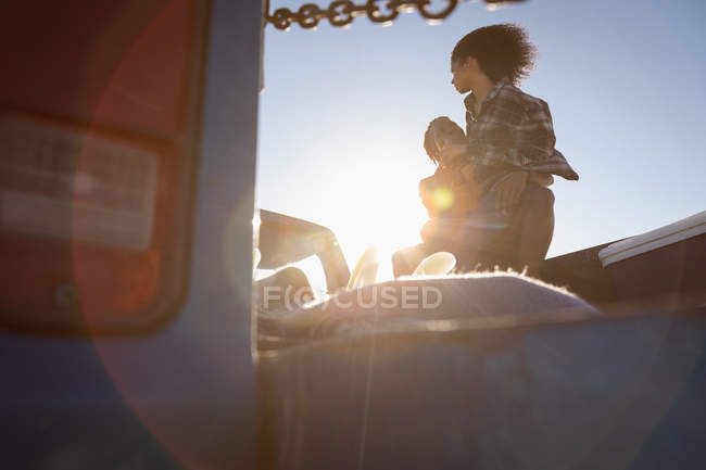 Низкий угол обзора мужчины, несущего женщину в машине в солнечный день — стоковое фото