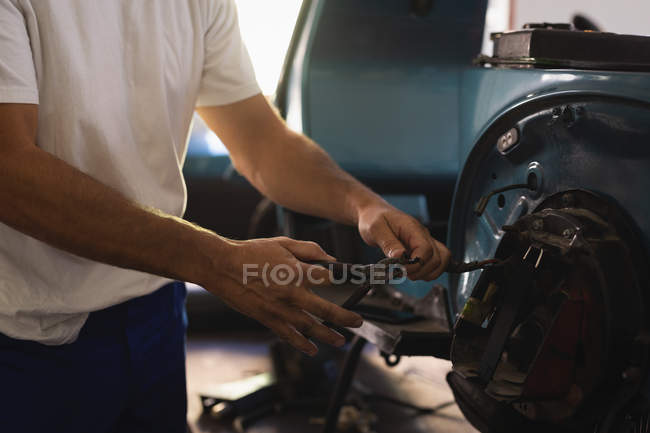Mid section of male bike mechanic repairing bike in garage — Stock Photo