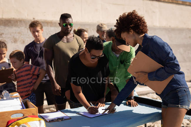 Вид спереди многоэтнических людей, записавшихся на день волонтера на пляже — стоковое фото