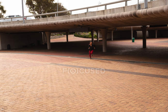 Frontansicht einer jungen Mischlingshündin, die nahe der Fußgängerbrücke in der Stadt läuft — Stockfoto