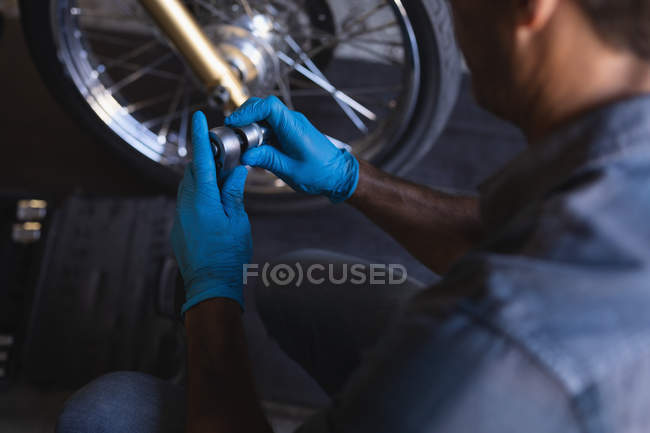 Vue grand angle du mécanicien cycliste caucasien travaillant dans le garage avec clé à cliquet — Photo de stock