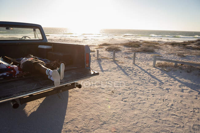 Side view of man lying down in car at beach on a sunny day — Stock Photo