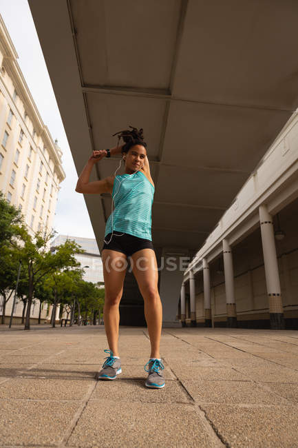 Vue à angle bas de l'ajustement Dosage mixte femme exercice d'étirement dans la rue dans la ville — Photo de stock