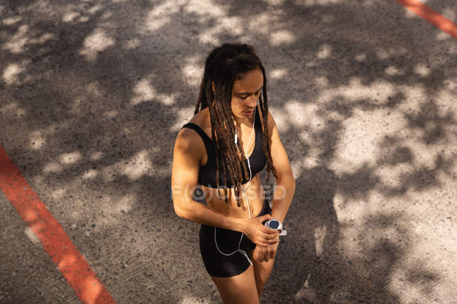 Vista ad alto angolo della giovane donna di razza mista utilizzando smartwatch per strada in città — Foto stock